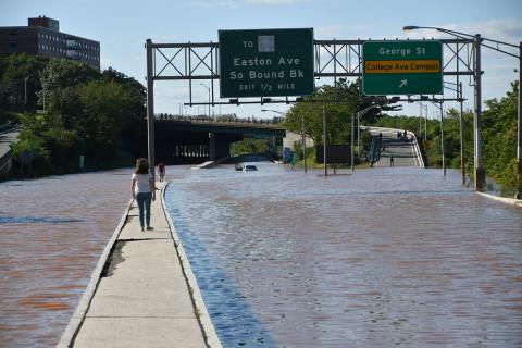 Here, a woman walks on median in the middle of a flooded highway in New Brunswick, New Jersey, after Hurricane Ida