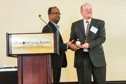 Shree Vikas, director of market intelligence and business analysis at ConocoPhillips, gives Andy Kleit the Senior Fellow Award 