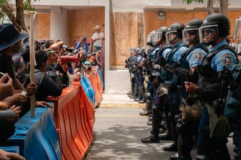 An image from the film "DisemPOWERed: Puerto Rico's Perfect Storm" shows protesters stand facing police officers in Puerto Rico.