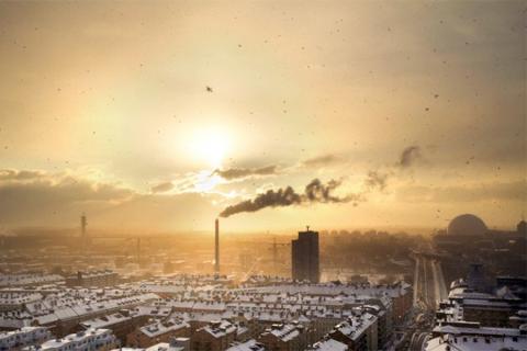 An industrial cityscape of a town filled with factories and air pollution at sunset. 