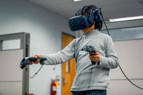 A woman uses virtual reality equipment at the Center for Immersive Experiences.
