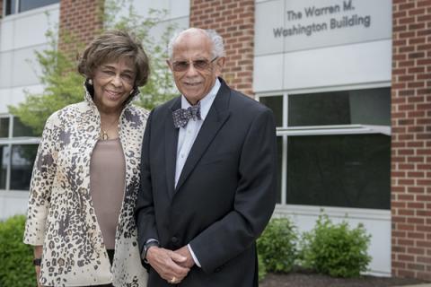 Warren and Mary Washington pose for photos at the entrance to the newly named Warren M. Washington Building 