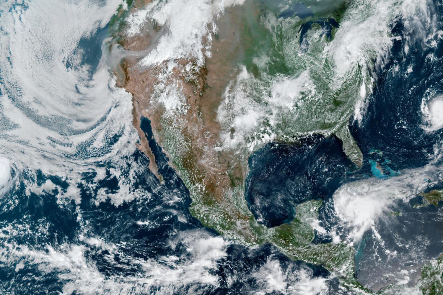 This satellite image captured in August 2021 over North America shows multiple storms offshore and smoke streaming