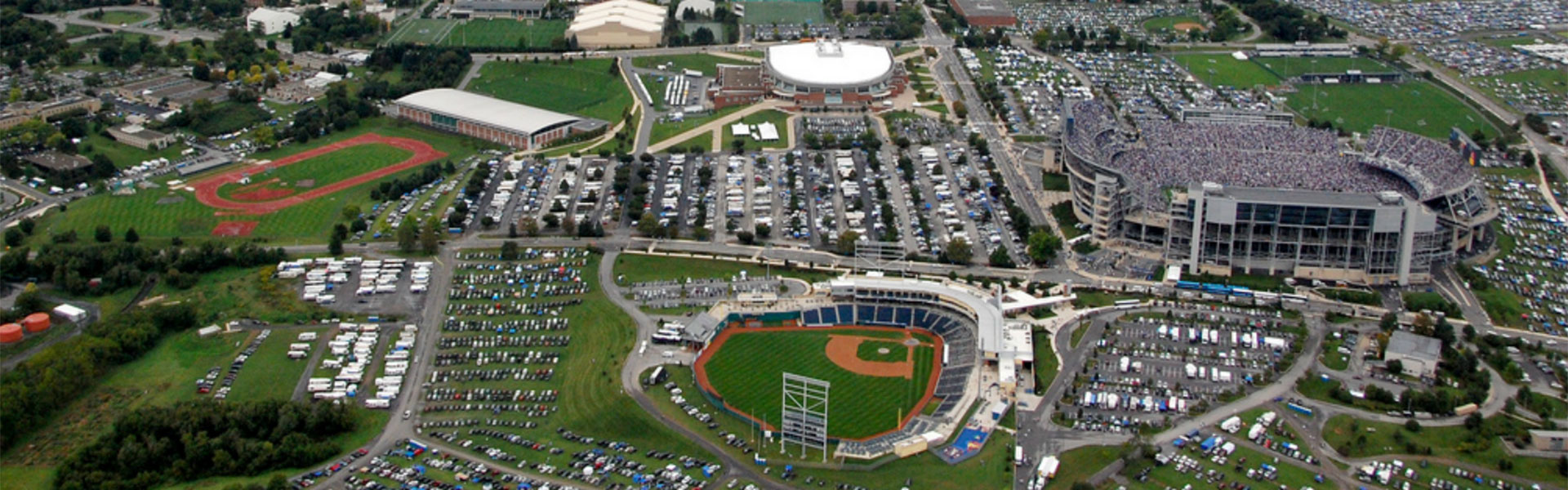 an aerial view of Medlar Field at Lubrano Park, Beaver Stadium filled with fans, Bryce Jordan Center, the running track, and the parking lots surrounding